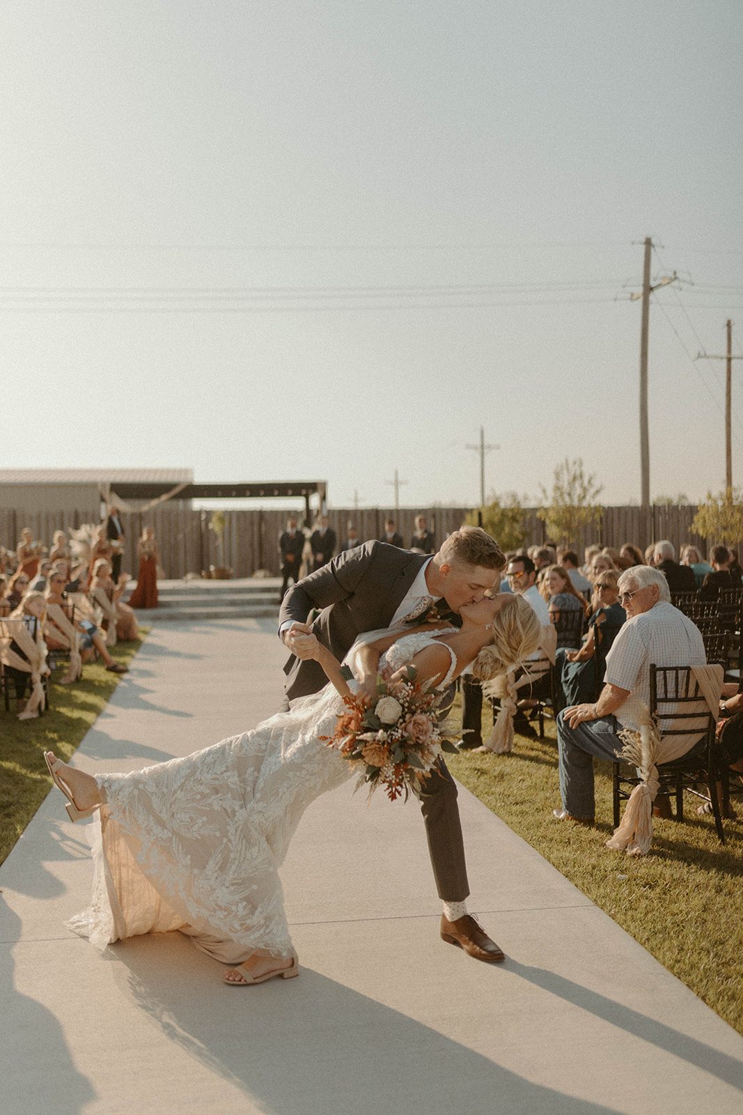 Groom dipping his bride at an outdoor ceremony